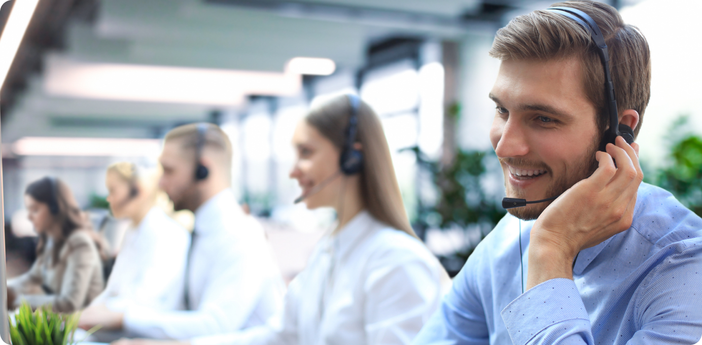 Smiling customer service representatives wearing headsets in a bright call center, illustrating the impact of strong employee retention strategies