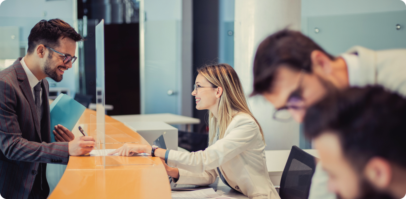 Smiling employee helping customer at front desk, showing the impact of frontline teams on personalized customer experience