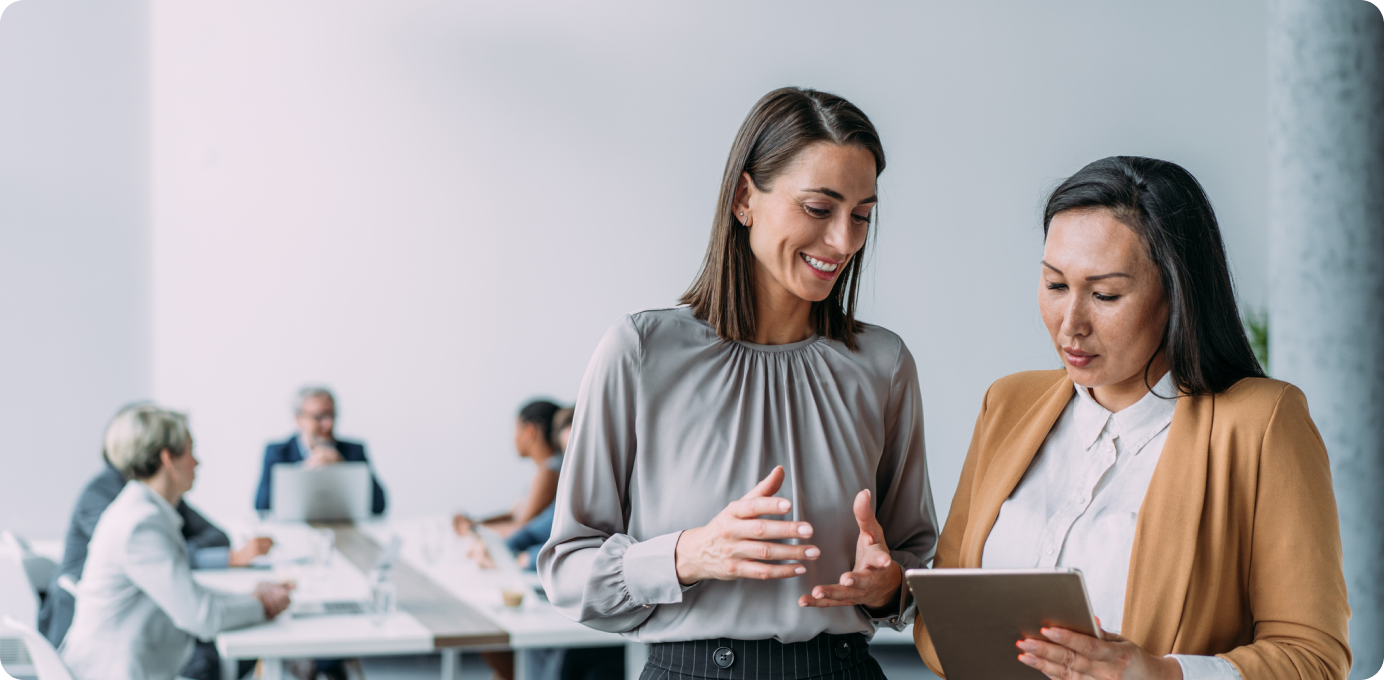 Two businesswomen reviewing data on a tablet, showing how data-driven decision making improves customer retention.