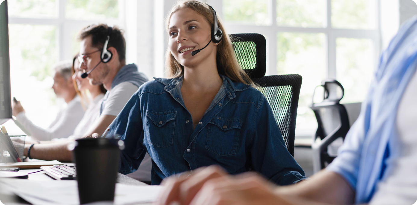 Smiling contact center employee with headset, representing positive coaching and feedback that strengthen frontline performance.